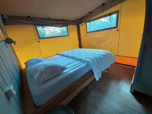 - un petit lit dans une chambre avec 2 fenêtres dans l'établissement Lodge Nature à Vigeois, à Vigeois