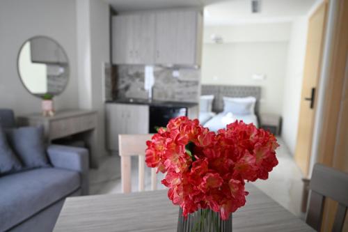 un jarrón de flores rojas sobre una mesa en la sala de estar en ALTA MARE, en Nea Peramos