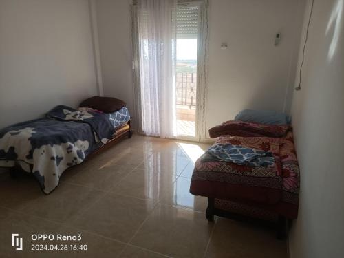 two beds sitting in a room with a window at F4 lpp Mostaganem Algérie in Mostaganem
