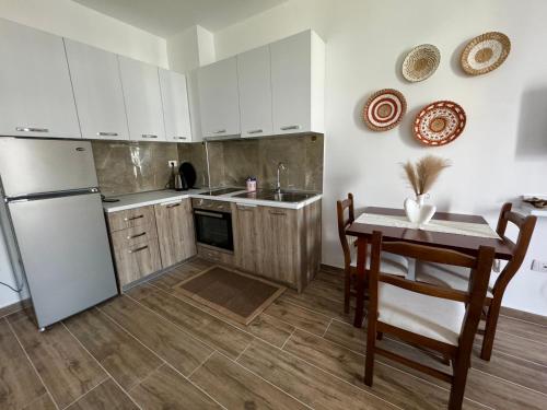 uma cozinha com armários brancos, uma mesa e um frigorífico em Sunset Serenity em Shëngjin