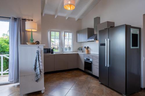 a kitchen with a stainless steel refrigerator and a window at Masbango Beach Resort in Jan Thiel