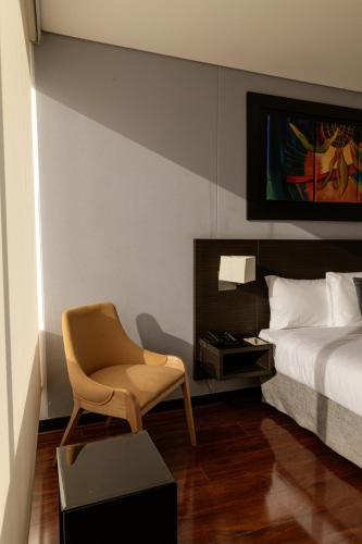 a bedroom with a bed and a chair and a table at One Sixteen Hotel in Bogotá