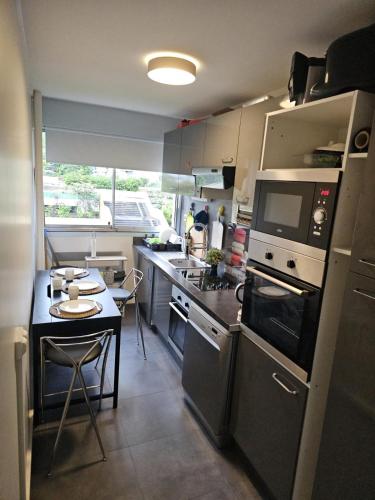 une petite cuisine avec une table et une cuisinière four supérieur dans l'établissement 4 Chambres television -Jean Macé, à Fontenay-sous-Bois