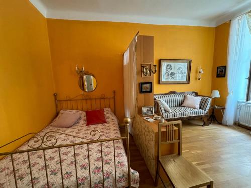 um quarto com paredes amarelas, uma cama e um sofá em The Place to be 2 "City Centre Apartments" em Viena