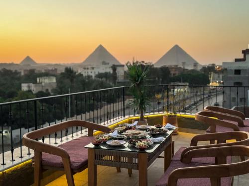 a table on a balcony with a view of the pyramids at Jimmy Pyramids Hotel in Cairo