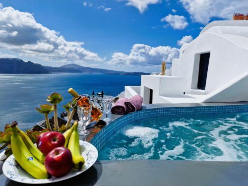 a bowl of fruit on a plate next to a swimming pool at Aqua & Terra Traditional Cave Houses in Oia