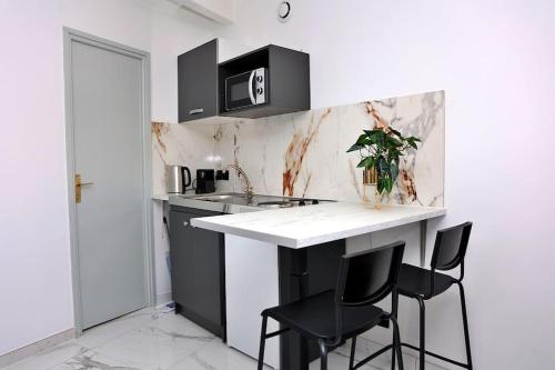 une cuisine avec un comptoir blanc et des tabourets noirs dans l'établissement Soleil du Sud Marseille StCharles Reformes Vieux Port, à Marseille