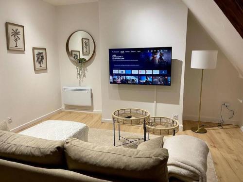 un salon avec un canapé et une télévision au mur dans l'établissement Appartement cosy centre ville, à Saint-Amand-Montrond