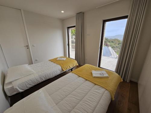 two beds in a room with a large window at Quinta do Penedo Real in Viana do Castelo