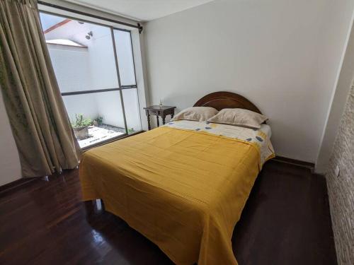 Un dormitorio con una cama con una manta amarilla. en Hermoso Departamento De Lujo, en Lima