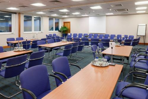 an empty room with tables and blue chairs at Holiday Inn Edinburgh Zoo by IHG in Edinburgh