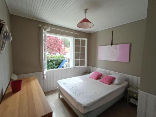 - une chambre avec un lit doté d'oreillers roses et d'une fenêtre dans l'établissement Soledam, à La Tranche-sur-Mer