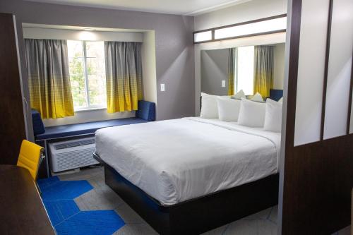 a bedroom with a large bed and two windows at Microtel Inn & Suites by Wyndham Searcy in Searcy