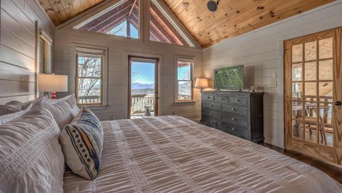 a bedroom with a bed and a tv and windows at Seven Turns to Sunrise in Blue Ridge