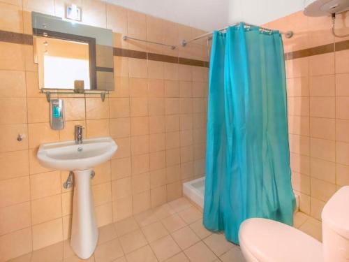 baño con lavabo y cortina de ducha azul en Ilioni studios 2, en Skala Kallirakhis