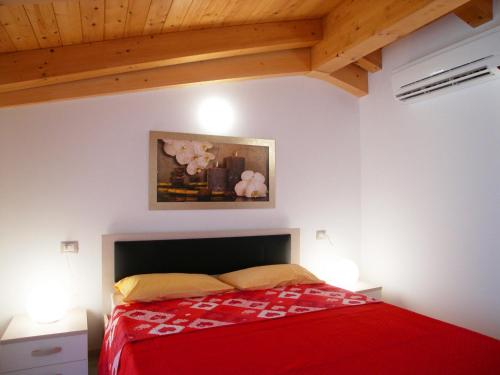 a bedroom with a bed with a red bedspread at Casa Tomani in Grado