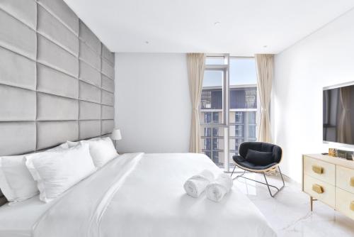 ein Schlafzimmer mit einem weißen Bett und einem schwarzen Stuhl in der Unterkunft Premium 2+1 BR condo in the heart of Bluewaters Island in Dubai