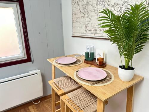 a table with two pink plates and a potted plant at Chambre indépendante au calme in Lamonzie-Montastruc