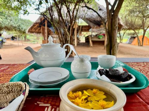 a tray with a teapot and a tea set on a table at Ego Swargarajje Yala Thissamaharama in Tissamaharama