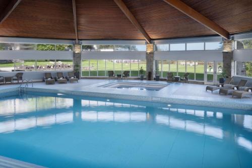 a large swimming pool in a large building with chairs at Delta Hotels by Marriott St Pierre Country Club in Chepstow