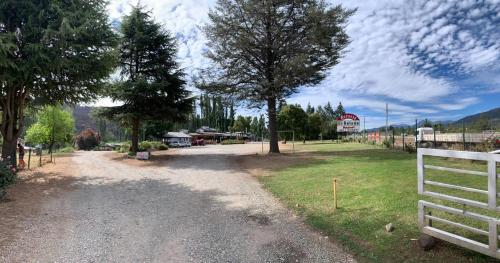 a dirt road with a white fence and a barn at Camping El Bolsón in El Bolsón
