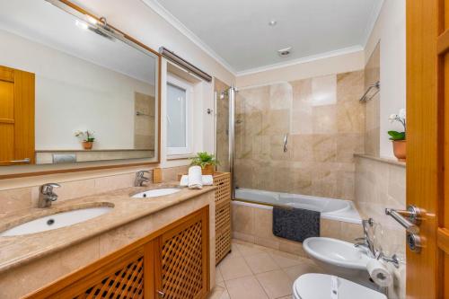 a bathroom with two sinks and a tub and a toilet at Avenue Apartment Vilamoura in Quarteira