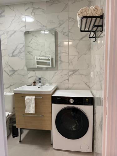 une salle de bain avec une machine à laver et un lavabo dans l'établissement WD Saint Roch - Appartement 102 - Métro 7 Proche Paris, à Villejuif