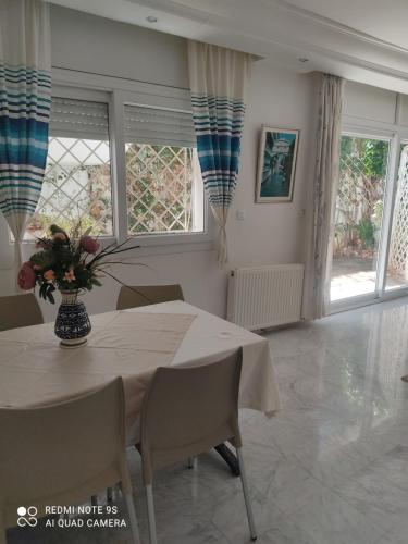 a dining room with a table with a vase of flowers on it at Villa avec j'ardin in Ariana