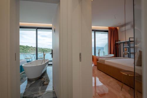 um quarto com uma banheira, uma cama, uma cama e uma janela em Siro Kerma Private Beach Villa em Sarandë