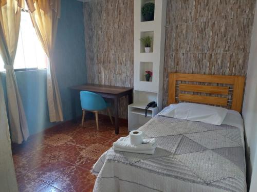 a bedroom with a bed and a desk and a chair at Hostal COLUMBIA in Moquegua