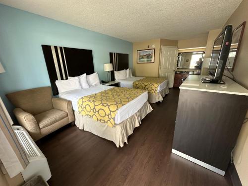 a hotel room with two beds and a chair at Baymont by Wyndham Thomasville in Thomasville