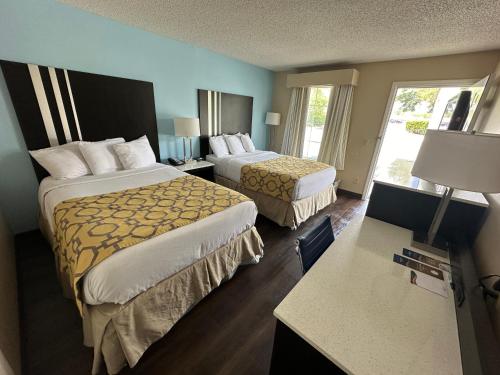 a hotel room with two beds and a desk at Baymont by Wyndham Thomasville in Thomasville
