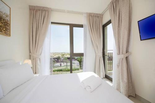 a bedroom with a white bed and a large window at Green Haven 3BR Villa-Golfside Grandeur-Emmar South in Dubai