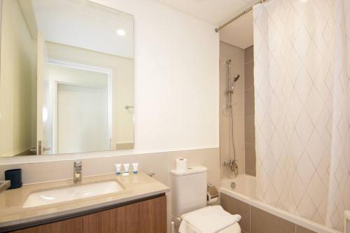 W łazience znajduje się umywalka, toaleta i lustro. w obiekcie Green Haven 3BR Villa-Golfside Grandeur-Emmar South w Dubaju