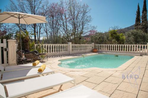een zwembad met een hek en een parasol bij Superb renovated villa 2 steps from Seillans in Seillans