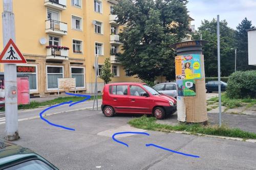une voiture rouge est garée dans un parking avec des flèches bleues dans l'établissement Apartmán BB-Centrum1, à Banská Bystrica