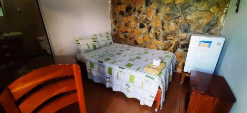 Dormitorio pequeño con cama y pared de piedra en Confort pichanaki, en Pichanaki