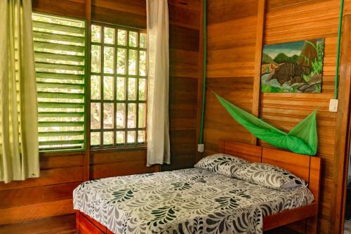 ein Schlafzimmer mit einem Bett in einem Zimmer mit Holzwänden in der Unterkunft Cabañas Dechi in Puerto Nariño