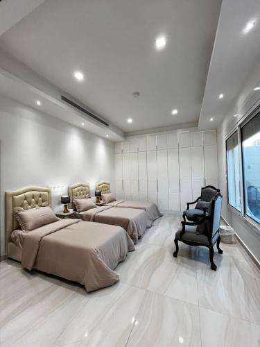 1 dormitorio con 3 camas, silla y ventana en شقة مريحة فاخرة Cozy apartment, luxury with fun, en Yeda