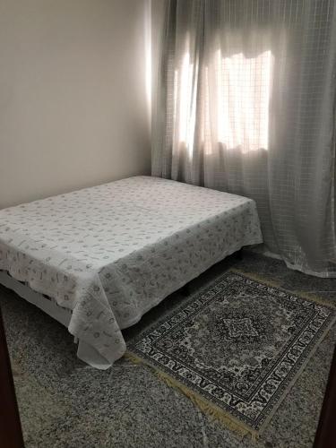 Cama en habitación con cortina y alfombra en Casa Iriri, en Anchieta
