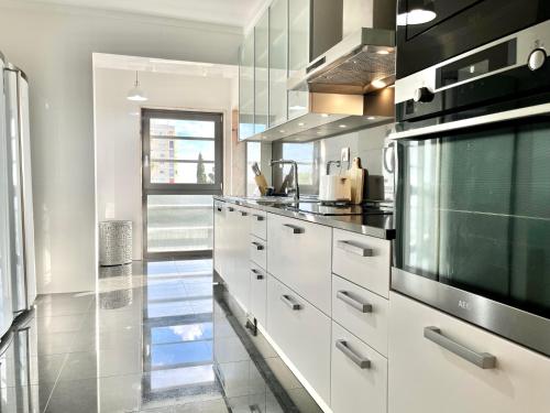 里斯本Modern & Spacious APT with River View的配有白色橱柜和黑色家电的厨房