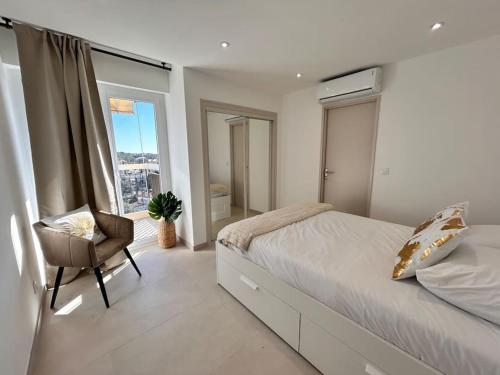 une chambre avec un lit, une chaise et une fenêtre dans l'établissement Prestige - 4 pers Neuf Vue Mer - Hyper centre, à Saint-Raphaël