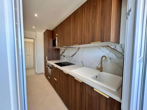 une cuisine avec un évier et des armoires en bois dans l'établissement Prestige - 4 pers Neuf Vue Mer - Hyper centre, à Saint-Raphaël