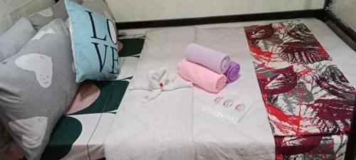 a bed with a white comforter with a tie and other items at Homey Inn-Olango Island Staycation ,block 1 lot 15 in Lapu Lapu City