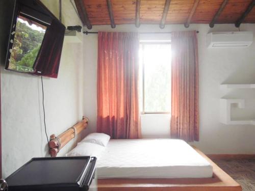 Schlafzimmer mit einem Bett, einem TV und einem Fenster in der Unterkunft Finca familiar privada para el descanso in Puerto Triunfo