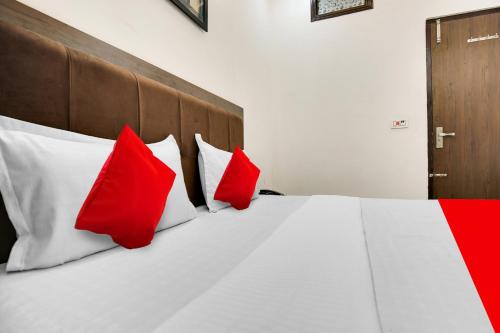 a bedroom with a bed with red and white pillows at Hotel O King Star Residency in Bathinda