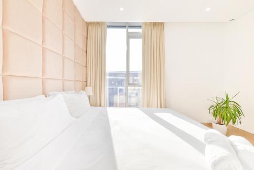 a bedroom with a white bed and a window at Premium 2+1 BR condo in the heart of Bluewaters Island in Dubai