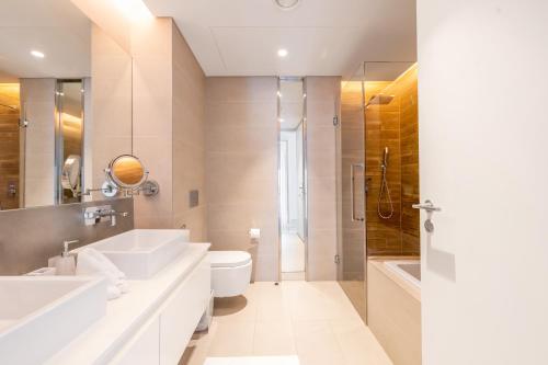 a bathroom with two sinks and a toilet and a shower at Premium 2+1 BR condo in the heart of Bluewaters Island in Dubai