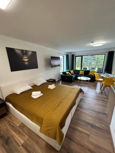a bedroom with a large bed and a living room at Domki i Apartamenty Wypoczynkowe z jacuzzi Lidzbark in Lidzbark