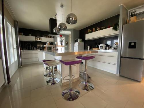 a kitchen with purple bar stools and a refrigerator at Villa contemporaine avec piscine in Romans-sur-Isère